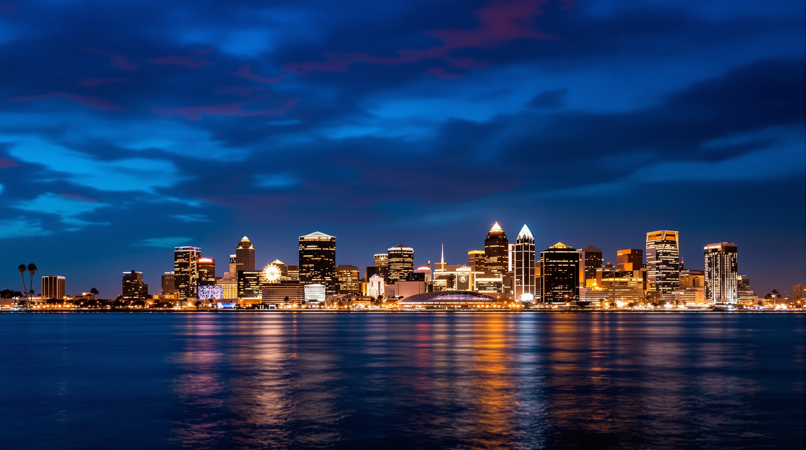 A city skyline reflected across the water at dusk